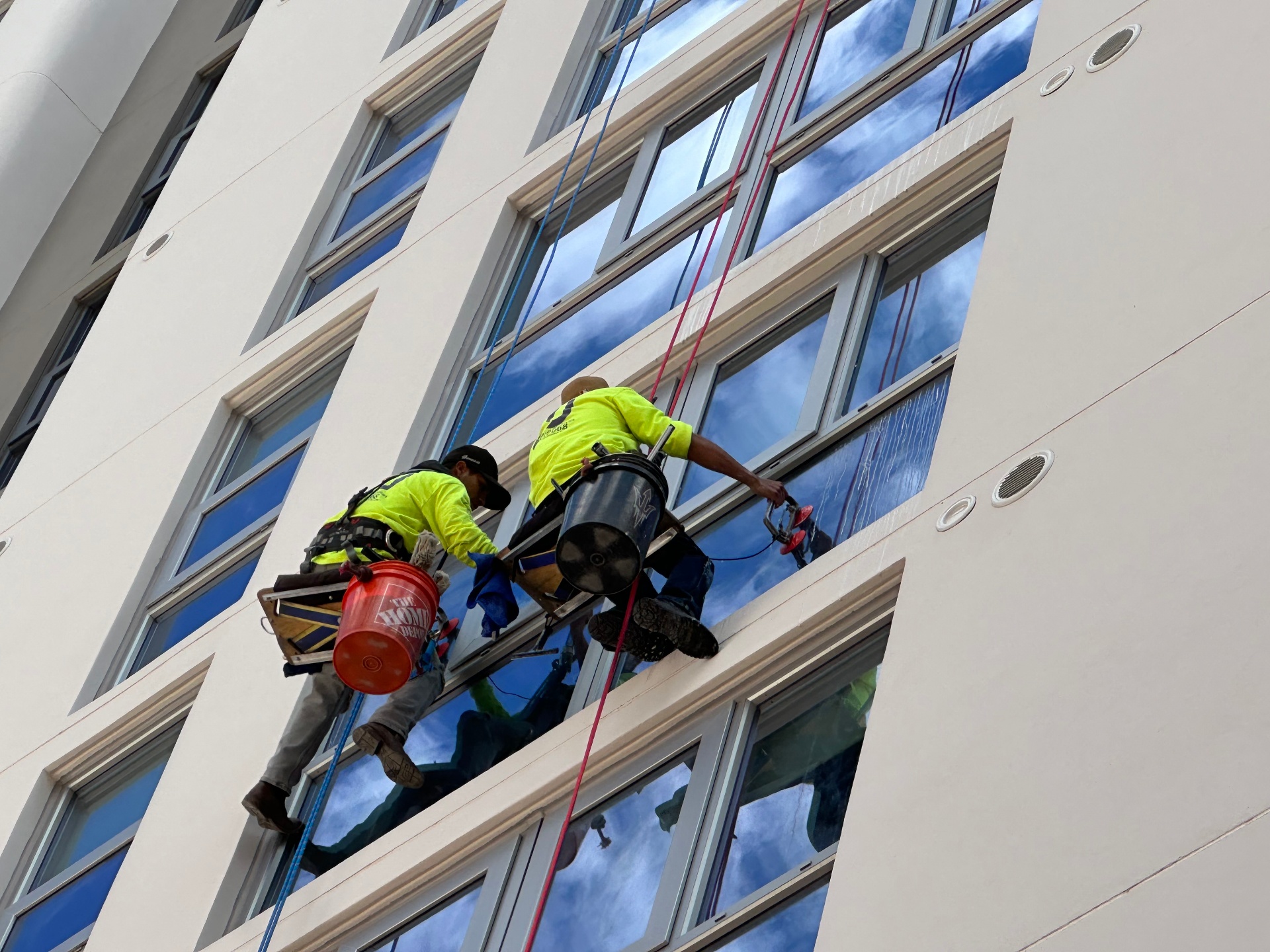Two rope-access window cleaners suspended on the face of a high-rise building