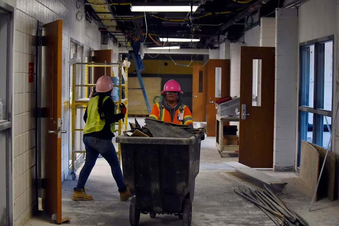 Hard-hatted JANI-WORKS crew clearing construction debris from a building corridor